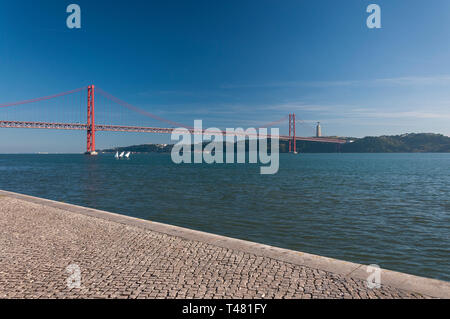 Drei kleine Segelboote am Fluss Tejo mit den 25 April Brücke auf der Hintergrund in der Stadt Lissabon, Portugal Stockfoto