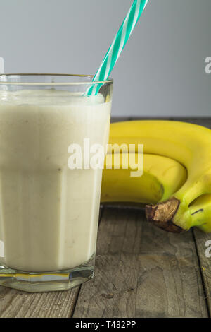 Lecker Banane Protein Shake auf Holz- Hintergrund. Schönen Milchshake mit Bananen im Hintergrund. Stockfoto