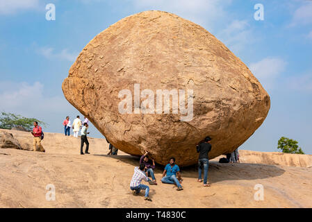 Horizontale Ansicht von Touristen vorgibt, Krishnas Butterball in Mahabalipuram, Indien zu halten. Stockfoto