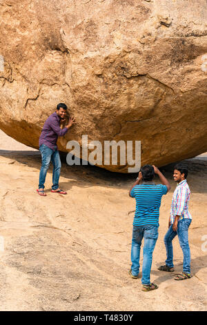 Vertikale Ansicht von Touristen vorgibt, Krishnas Butterball in Mahabalipuram, Indien zu halten. Stockfoto