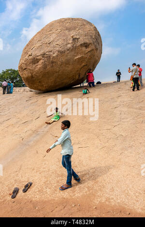 Vertikale Ansicht von Kindern in Mahabalipuram, Indien spielen neben Krishnas Butterball. Stockfoto