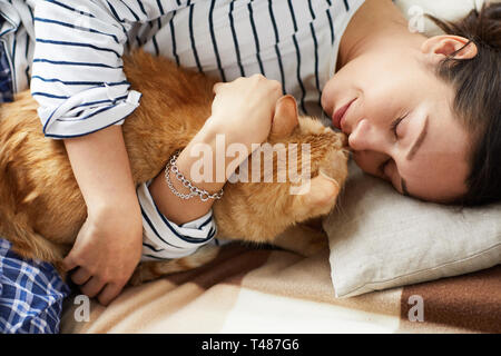 Junge Frau Kuscheln mit Cat Stockfoto