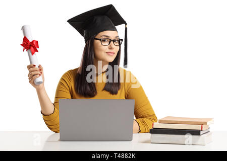 Junge Frau mit einem Abschluss hat und Diplom sitzt mit Laptop und Bücher auf weißem Hintergrund Stockfoto