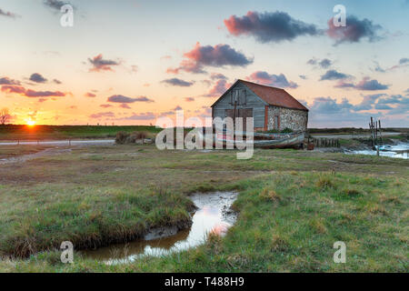 Einen atemberaubenden Sonnenuntergang über dem alten Kohle Scheune Thornham alten Hafen an der Küste von Norfolk Stockfoto