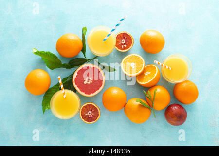 Orange und Grapefruit frisch gepressten Saft in Glas und frische Früchte auf einem blau leuchtenden Hintergrund, Ansicht von oben Stockfoto