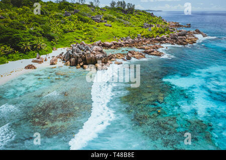 Tropical Beach Anse Cocos. La Digue Insel. Seychellen. Drone Luftaufnahme der Küstenlinie mit Blue Ocean Waves, einzigartige Granitfelsen und Unpassierbar Stockfoto