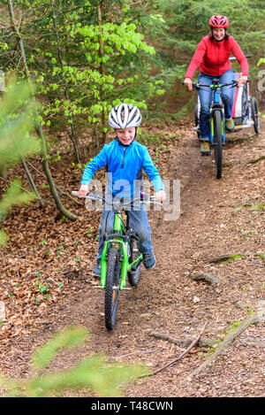 Motiviert junge Radfahren auf Forstweg durch Mutter Stockfoto