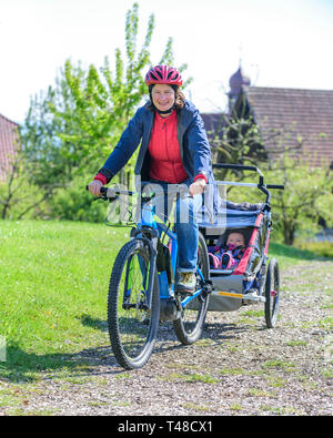 Frau Radfahren mit Anhänger und elektrische Unterstützung Stockfoto