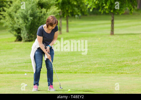 Frau am Setzen auf dem Golfplatz Stockfoto