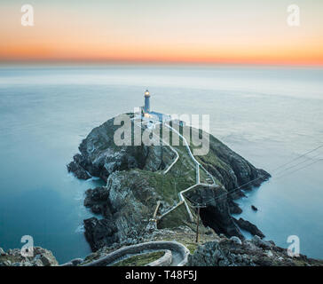 Am frühen Abend Sonnenuntergang Szene mit Blick aufs Meer in Richtung South Stack Lighthouse, Anglesey, Nordwales. Stockfoto