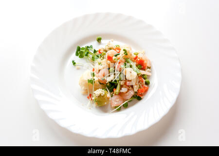 Couscous mit Gemüse, Garnelen und Radieschen auf einem weißen Teller Stockfoto