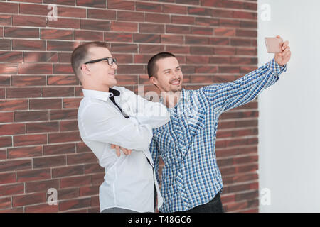 Zwei freundliche Mitarbeiter unter selfies stehen im Büro. Mensch und Technik Stockfoto