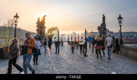 Touristen überqueren die berühmte Karlsbrücke in der Hauptstadt auf einem hellen Sonnenuntergang Abend Stockfoto