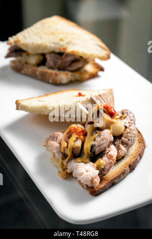 Berühmte traditionelle portugiesische bifana würzig mariniertes Schweinefleisch sandwich Snack mit Senf piri piri Sauce und Knoblauch in Lissabon Cafe Stockfoto