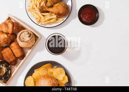 Frisch gebackene Brötchen, große Hamburger, gebraten knusprige Hähnchen und Pommes frites auf weißen Tisch - Ungesunde Lebensmittel Konzept Stockfoto