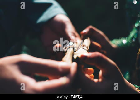 Ehepaar mit traditionellen Hochzeit Kleid Hochzeit Ringe, die in einem dunklen Beleuchtung. selektive Fokus Stockfoto