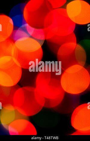 Sanft verschwommene Weihnachtsbaumfeenlichter leuchten in leuchtenden Rot-, Grün- und Goldtönen und schaffen einen warmen, festlichen Bokeh-Hintergrund voller Weihnachtszauber. Stockfoto