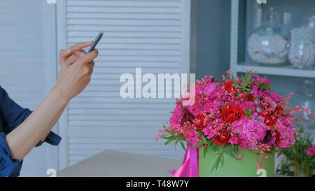 Frau unter Foto des Schönen Blumenstrauß mit Smartphone Stockfoto