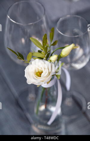 Transparentes Glas Vase mit Blumenstrauß vor Hintergrund der Tabelle Einstellung im modernen Restaurant. Wein und Wasser Gläser stehen in der Zeile auf Holz Stockfoto