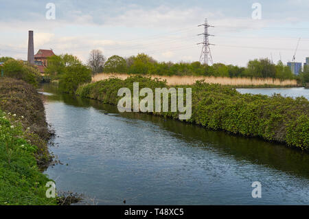 Coppermill Stream im Frühjahr, auf Feuchtgebiete, Walthamstow North East London UK, mit dem viktorianischen Motor Haus Gebäude im Hintergrund Stockfoto