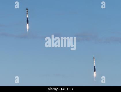 Zwei SpaceX Falcon Schwere wiederverwendbare Rocket Booster Abstieg nach Durchführung der saudi-arabischen Arabsat 6A communications Satelliten in eine Erdumlaufbahn vom Kennedy Space Center April 11, 2019 in Cape Canaveral, Florida aufrecht zu landen. Dies ist der erste kommerzielle Start der massiven 27-Motor Koloss, der derzeit leistungsstärkste Rakete jetzt auf der Erde. Stockfoto