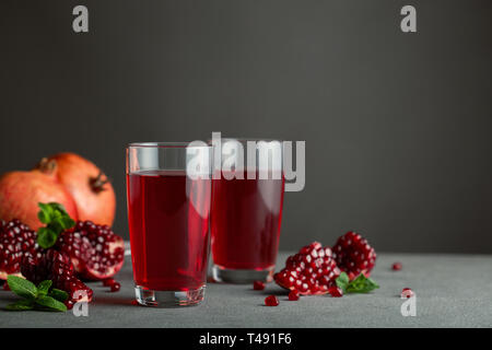 Granatapfel Saft in ein zwei Gläser auf grauem Hintergrund. Stockfoto