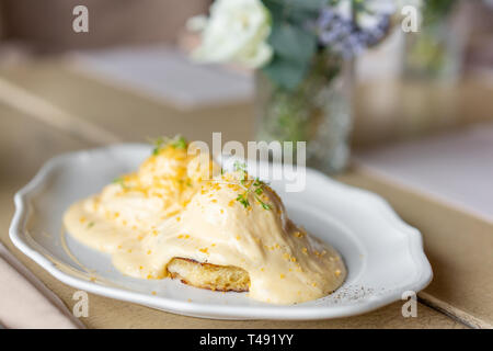 Ei Benedikt auf warmen Toast Brioche. Zwei Eier, leckeren Sauce Hollandaise. Licht am Morgen das Frühstück auf dem Tisch im Restaurant. Stockfoto