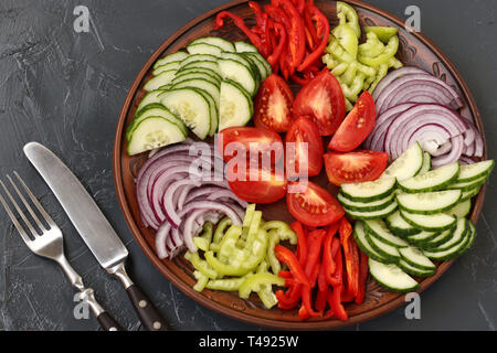 Gesunder Salat von Tomaten, roten Zwiebeln, Paprika und Gurken ist auf einem Schild auf einem dunklen Hintergrund der Ansicht von Oben entfernt Stockfoto