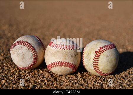 Foto von drei Spiel verwendet Baseballs auf einem Baseball infield an einem sonnigen Tag Stockfoto