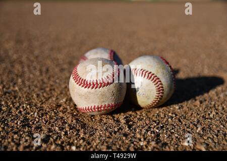 Foto von drei Spiel verwendet Baseballs auf einem Baseball infield an einem sonnigen Tag Stockfoto