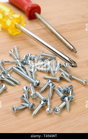 Metall und Holz Schrauben auf Holz mit roten und gelben Schraubendreher Stockfoto