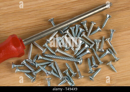 Rote Schraubendreher und Schrauben auf einem Holztisch Stockfoto