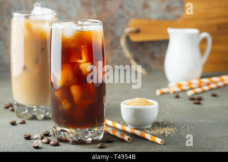 Eis Kaffee in ein hohes Glas mit Sahne über und Kaffeebohnen gegossen. Kalten Sommer trinken auf einem braunen Rusty Hintergrund Stockfoto