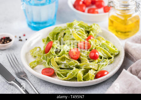 Grüne Spinat Nudeln mit Sahnesoße und Tomaten auf einer Platte. Italienische Küche essen. Detailansicht, horizontale Ausrichtung Stockfoto