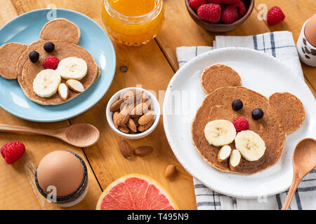 Kinder Frühstück mit Pfannkuchen und Früchte auf einem Holztisch. Food Art Tier geformt Pfannkuchen, lustige kreative Idee Stockfoto