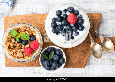 Joghurt, Müsli und Heidelbeeren im Glas auf Holzbrett, Table Top anzeigen. Gesund essen, gesund leben, Diät oder Gewichtsverlust Konzept Stockfoto