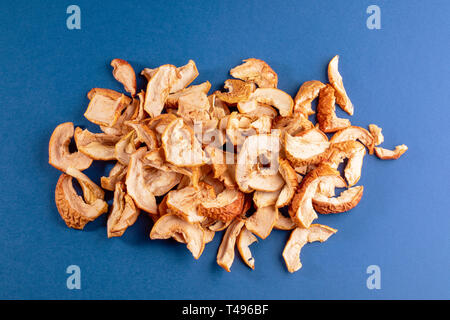 Chaotischen Haufen getrocknete Apfelscheiben auf blauem Hintergrund. Obst gesundes Essen. Ansicht von oben. Stockfoto