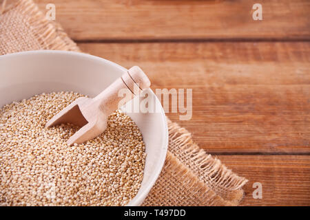 Trockene Quinoa in einer Schüssel mit Holz- Schaufel auf den Holztisch. Ansicht von oben. Kopieren Sie Platz. Stockfoto