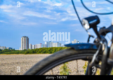 Blick über die unfocused Vorderrad eines Fahrrades über ein Feld zum Satelliten Stadt Gropiusstadt in Berlin-Neukölln. Stockfoto