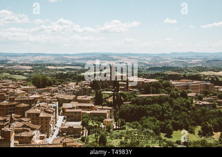 Panoramablick auf Siena Stadt mit historischen Gebäuden und weit weg die grünen Felder von Siena Dom (Duomo di Siena). Sommer sonnigen Tag und dramatische bl Stockfoto