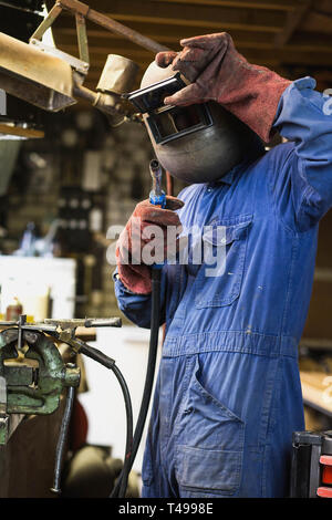 Schweißer ist Schweißen in der Garage, industrielle Arbeiter Arbeiter in der Fabrik schweißen Stahlkonstruktion Stockfoto