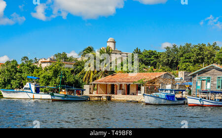 Kubanische Fischerboote und Dorfhäuser mit Jagua spanischen Burg Wände im Hintergrund, in der Provinz Cienfuegos, Kuba Stockfoto