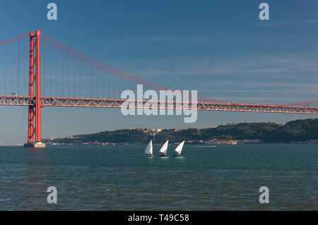 Drei kleine Segelboote am Fluss Tejo mit den 25 April Brücke auf der Hintergrund in der Stadt Lissabon, Portugal Stockfoto