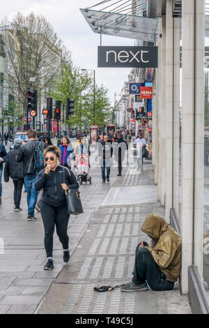 Leute, die ein Mann Betteln in der Oxford Street im Londoner West End. Stockfoto