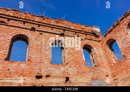 Die Ruinen einer alten Backsteingebäude aus rotem Backstein. Die Schornsteine der verlassenen Gebäude zerstört werden gegen den blauen Himmel. Stockfoto