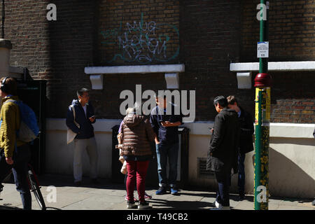 Junge Menschen mit Smartphone auf der Straße in der Brick Lane, Spitalfields, London Stockfoto