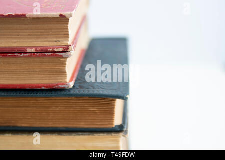 Alte, abgetragene Bücher auf weisse Oberfläche gestapelt schließen oben mit Kopie Raum Stockfoto