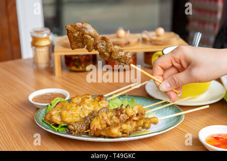 Frau Hand hält eine Stücke von Satay Stockfoto