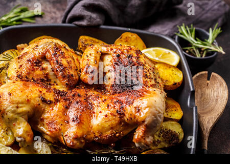 Gebratene ganze tabaka Huhn mit Kartoffeln in einer Grillpfanne, dunklen Hintergrund. Stockfoto