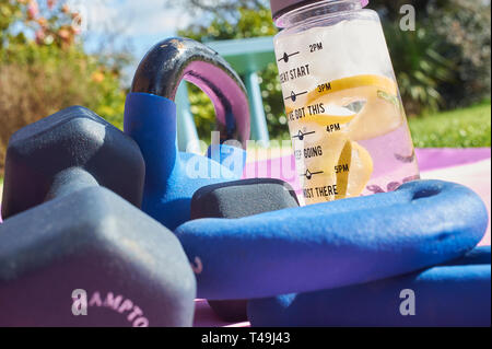 Eine Auswahl an Hanteln Kettlebells und eine Flasche frisches Wasser mit Limette und Zitrone Bestandteile sein. Stockfoto